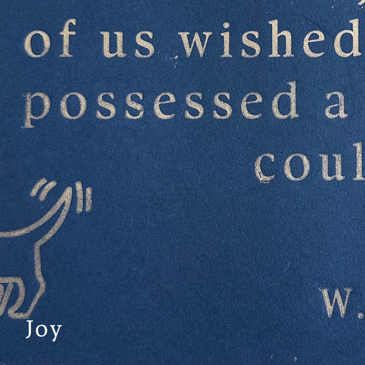 Hand printed gold text on a dark blue paper background with a hand-drawn figure, featuring the word 'Joy'.