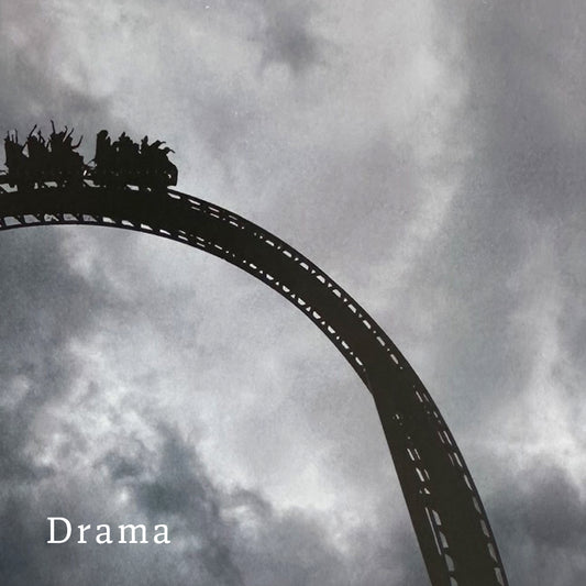 Cropped shot of a silhouette of a roller coaster with 'Drama' text against a cloudy sky
